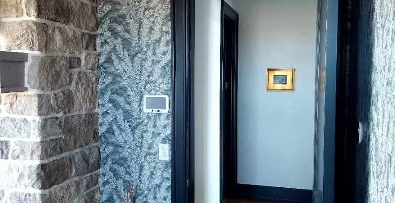 Textured blue feather wallcovering in an entryway beside a stone wall