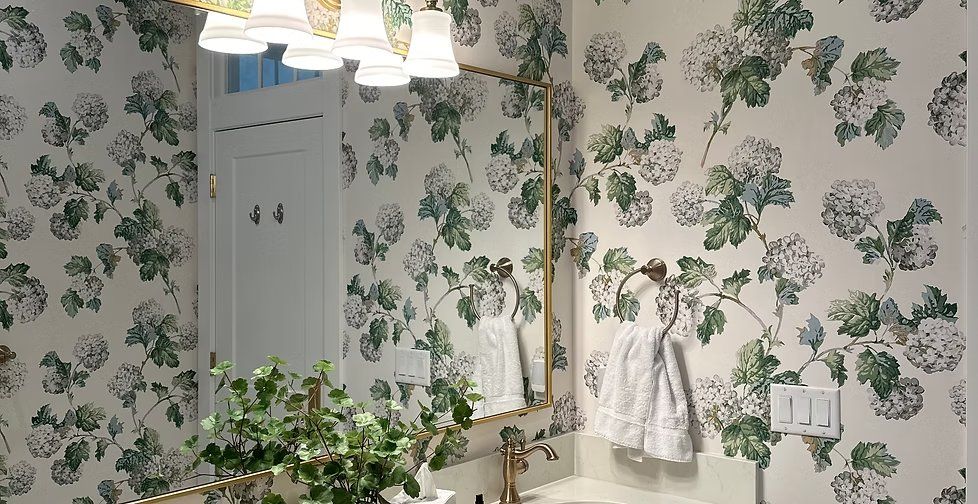 Green hydrangea floral wallpaper in a powder room with a gold mirror