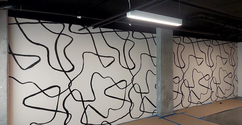 Black abstract line-art mural across a commercial parking structure wall